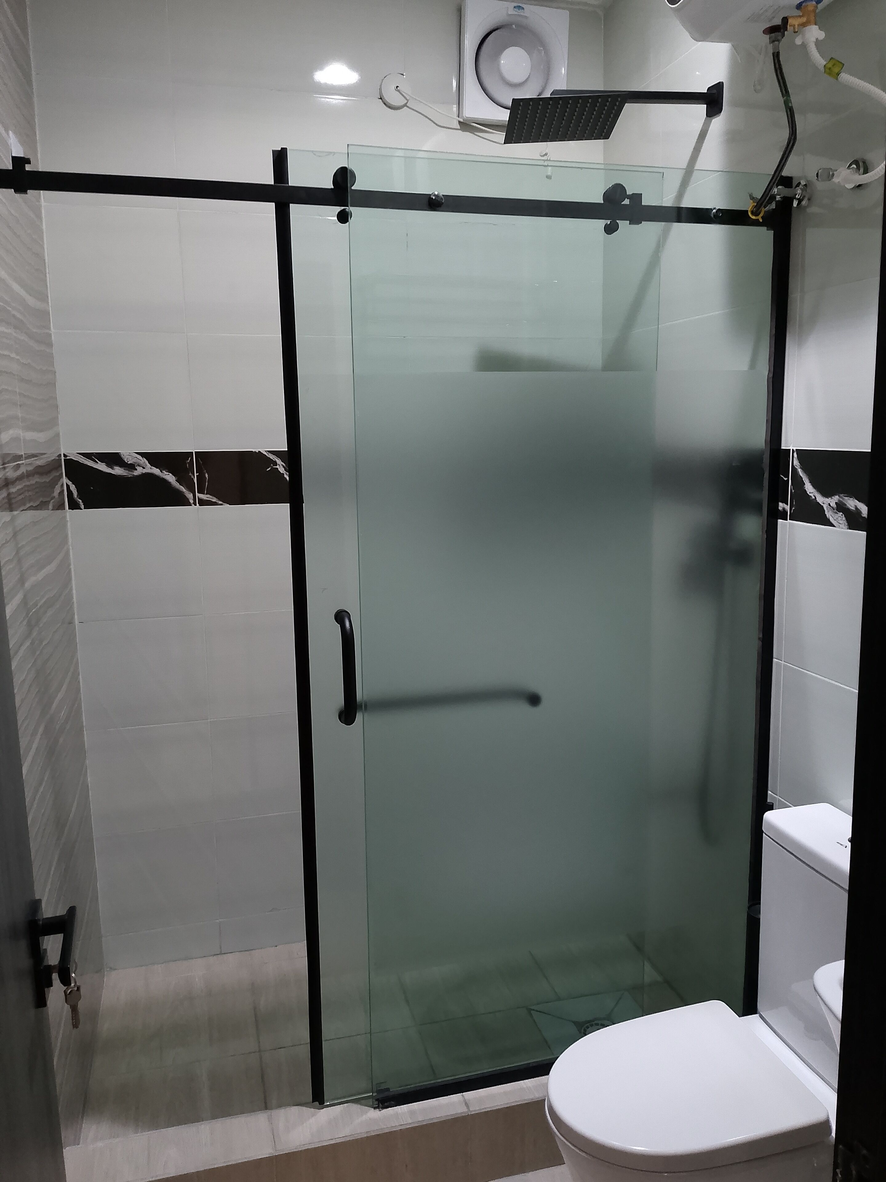 Une salle de bain avec une douche à parois de verre, des toilettes et un porte-serviettes.