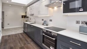 A modern kitchen with dark cabinets, a white countertop, a built-in oven, and a microwave. - The Old Hotel - Mad Alice (Clifton)
