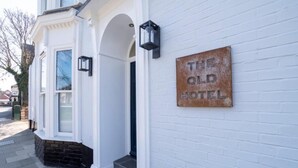 Een wit gebouw met een bord waarop 'THE OLD HOTEL' staat.