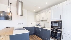 Een moderne keuken met een centraal eiland, witte kasten en inbouwovens.