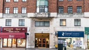Un immeuble portant une enseigne « Dudley Court », un restaurant appelé « Saffronis » et une agence immobilière nommée « SanaEstates ».