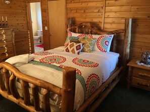 Een houten bed met hoofdeinde, een nachtkastje van hout en een dressoir met laden.