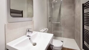 A modern bathroom with a white sink, toilet, and glass-enclosed shower.