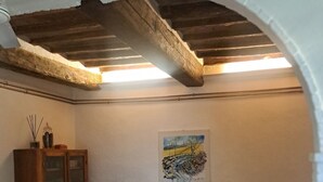 A cozy living room with a wooden ceiling, a grey sofa with floral cushions, a wooden cabinet, and a painting on the wall. - Santacaterina, Your oasis of peace overlooking the historic walls of Sansepolcro (Sansepolcro)