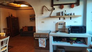 A cozy kitchen with a stove, microwave, and wooden shelves. - Santacaterina, Your oasis of peace overlooking the historic walls of Sansepolcro (Sansepolcro)