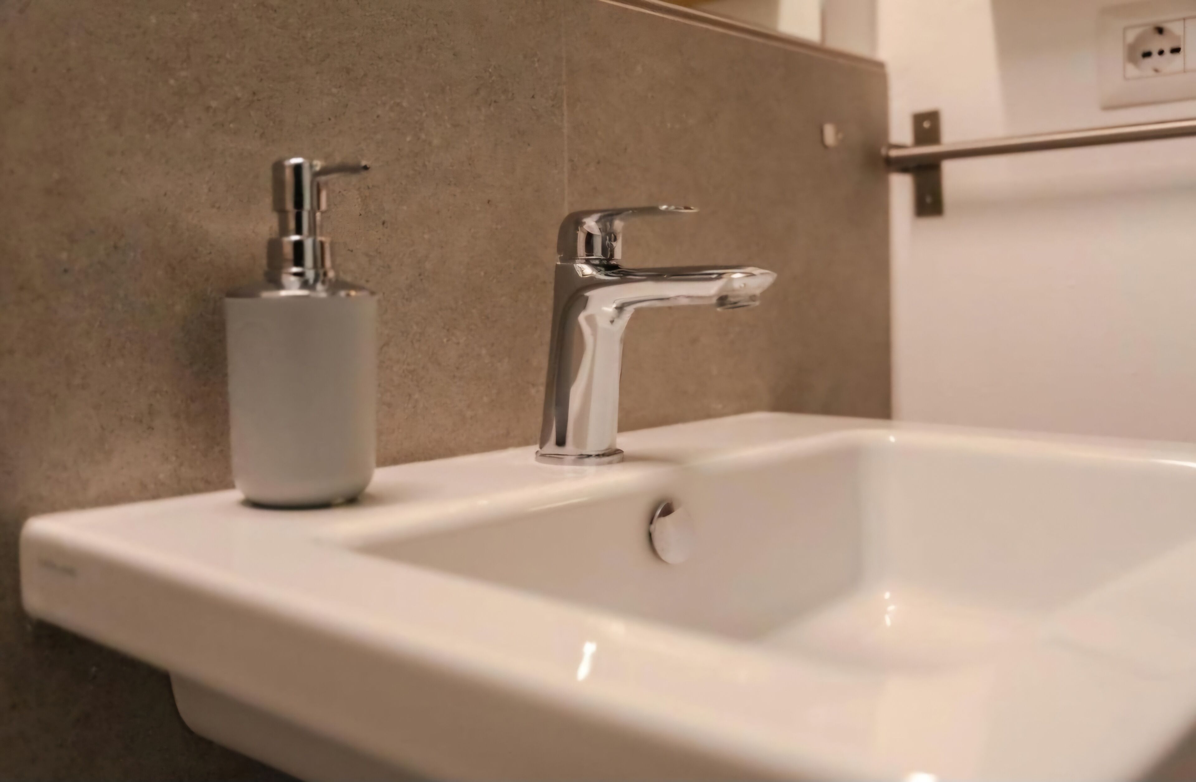 A bathroom sink with a chrome faucet and a soap dispenser.