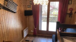 A wooden room with a bed, a table, and a window with curtains. - View mountain, terrace, tv, ski locker, 18m², Le Grand Bornand (Le Grand-Bornand)
