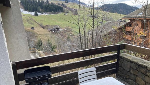 A balcony with a grill, a table, and a stone wall. - View mountain, terrace, tv, ski locker, 18m², Le Grand Bornand (Le Grand-Bornand)