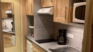 A compact kitchen with wooden cabinets, a microwave, a coffee maker, and a dishwasher. - View mountain, terrace, tv, ski locker, 18m², Le Grand Bornand (Le Grand-Bornand)