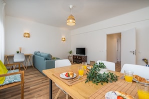 A modern living room with a sofa, dining table, and TV. - #281 Telecomunicações by Home Holidays (Albufeira)