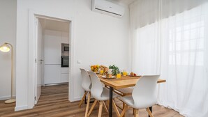 A dining area with a wooden table, white chairs, and breakfast items. - #281 Telecomunicações by Home Holidays (Albufeira)