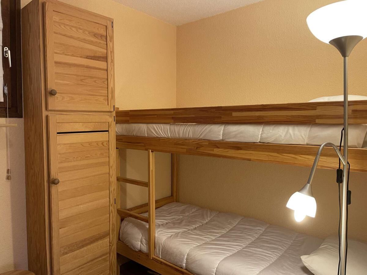 Ein Stockbett mit Schreibtisch und Lampe, ein Holzschrank und ein an der Wand befestigtes Regal.