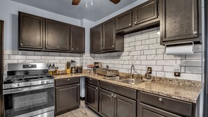 A modern kitchen with dark cabinets, a stainless steel stove, and a granite countertop. - Family-Friendly 6-bedroom house in Charming Buffalo with WiFi, AC (Buffalo)