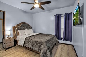 A bedroom with a bed, a nightstand, a ceiling fan, and a TV mounted on the wall. - Family-Friendly 6-bedroom house in Charming Buffalo with WiFi, AC (Buffalo)
