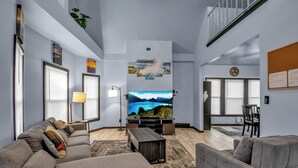 A modern living room with a large flat-screen TV, grey sofas, a wooden coffee table, and a patterned rug. - Family-Friendly 6-bedroom house in Charming Buffalo with WiFi, AC (Buffalo)