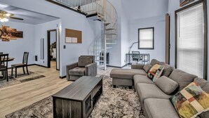 A spacious living room with a large sectional sofa, a coffee table, and a staircase leading to an upper level. - Family-Friendly 6-bedroom house in Charming Buffalo with WiFi, AC (Buffalo)