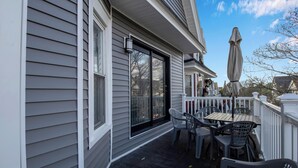 A covered patio with a table and chairs, a sliding glass door, and a white railing. - Family-Friendly 6-bedroom house in Charming Buffalo with WiFi, AC (Buffalo)