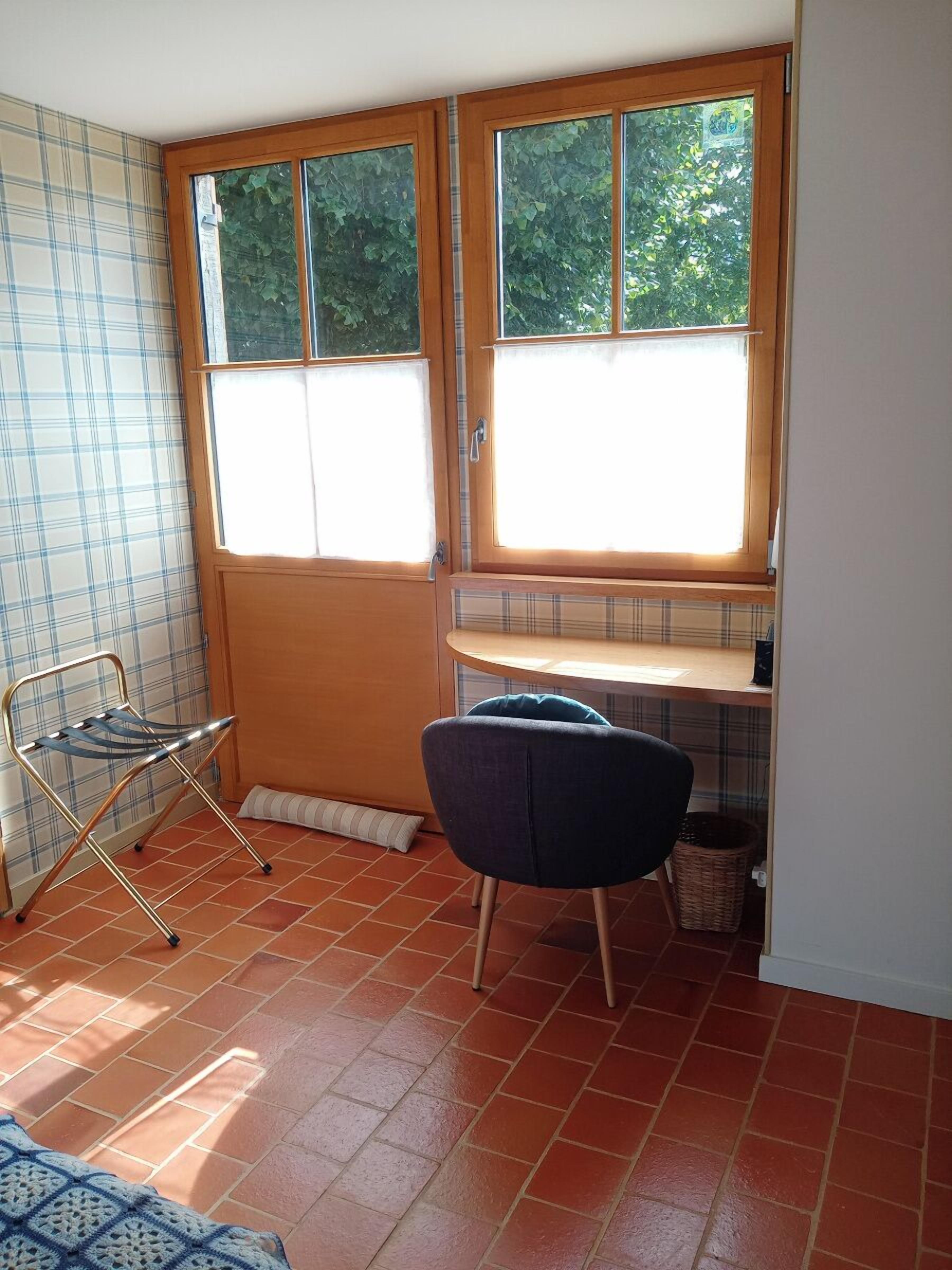 A small room with a window, a chair, a table, and a radiator.