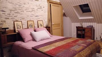A bedroom with a bed, a wooden door, a nightstand, and a dresser.