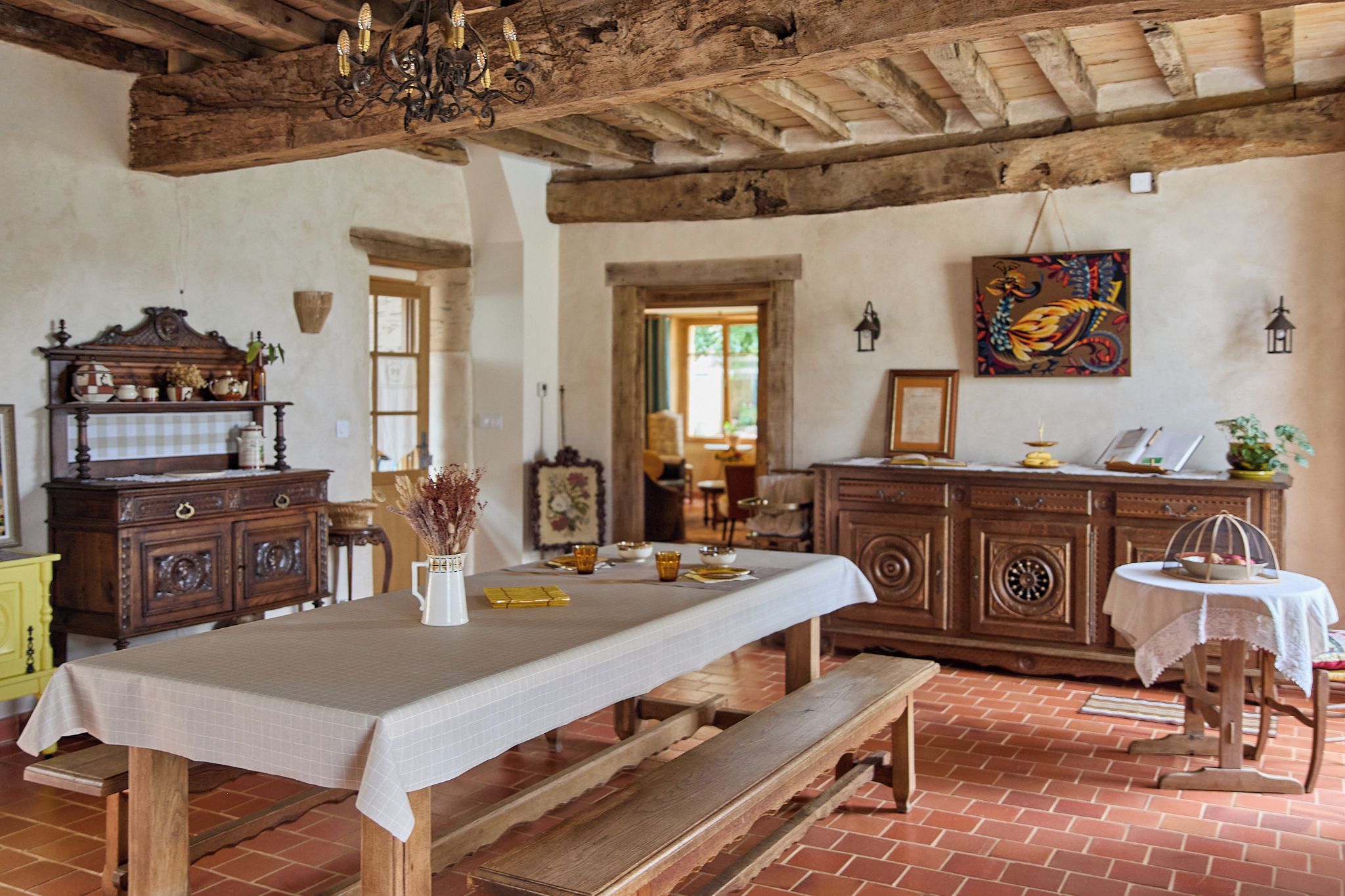 A rustic dining area with a long table, benches, and a wooden bench.