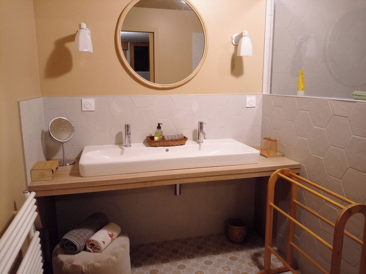 A bathroom with a white sink, a mirror above it, and a towel rack.