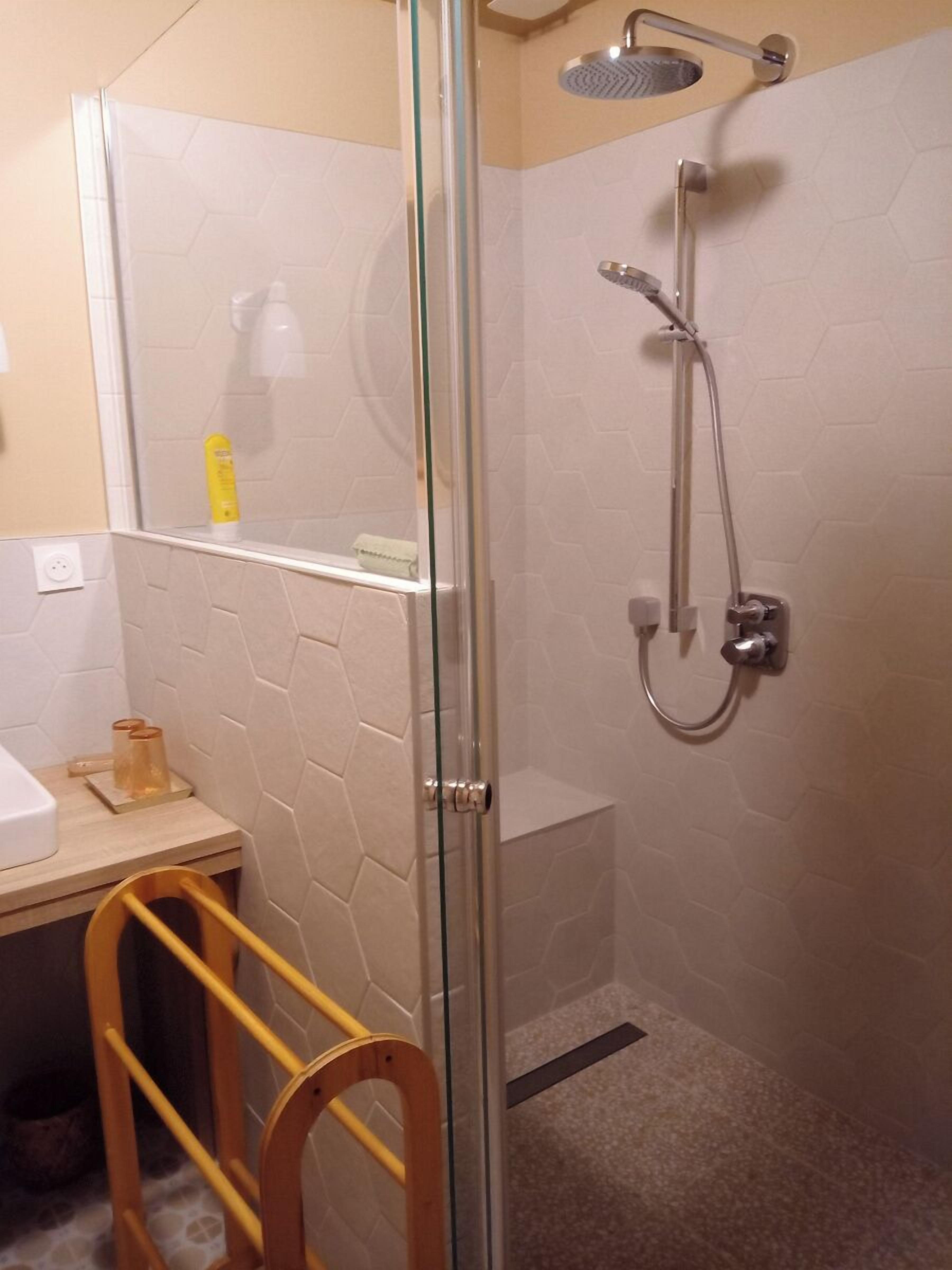 Ducha envuelta en vidrio con cabezal de ducha manual y llave instalada en la pared.