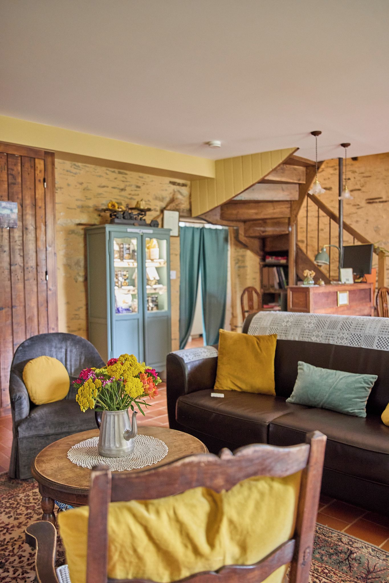 A cozy living room with a wooden staircase, a sofa, a chair, and a cabinet.