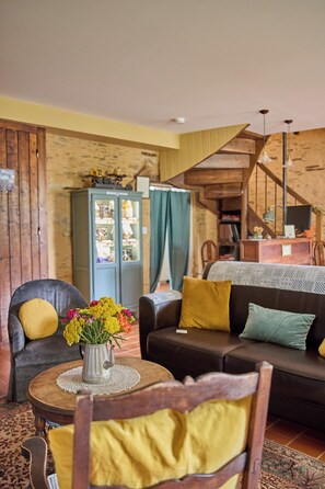A cozy living room with a wooden staircase, a sofa, a chair, and a cabinet. - à la Mainguère (Brece)