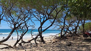 A beach with trees and a red vehicle. - Villa Quebrada Estate (Cóbano)