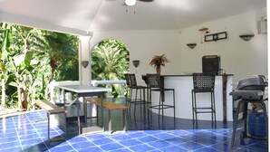 A covered outdoor area with a table and chairs, a ceiling fan, and a speaker. - Villa Quebrada Estate (Cóbano)