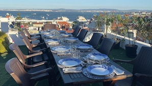 An outdoor dining area with a view of the sea and cityscape. - TheHOUSE - Your luxury home (Lisboa)