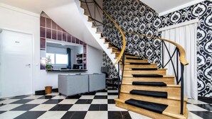 A staircase with a black and white checkered floor, a patterned wall, and a modern kitchen area with a grey countertop and cabinets. - TheHOUSE - Your luxury home (Lisboa)