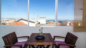 A balcony with a wooden table and two chairs, overlooking a cityscape with buildings and a clear sky. - TheHOUSE - Your luxury home (Lisboa)