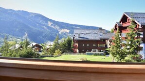 Hotel med udsigt til bjerge, en stor bygning og en mindre struktur i forgrunden.