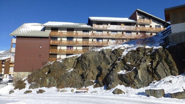 A multi-story hotel with balconies, situated on a snow-covered slope with rocky terrain. - 100m from ski slopes, 3rd floor, tv, 27m², Alpe d'Huez (L'Alpe d'Huez)