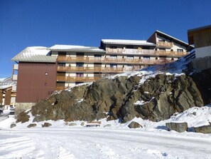 A multi-story hotel with balconies, situated on a snow-covered slope with rocky terrain. - 100m from ski slopes, 3rd floor, tv, 27m², Alpe d'Huez (L'Alpe d'Huez)
