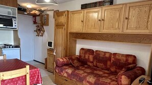 A compact living space with a kitchenette, a sofa, a dining table, and a ceiling fan. - 100m from ski slopes, 3rd floor, tv, 27m², Alpe d'Huez (L'Alpe d'Huez)
