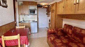 A compact kitchen with a built-in oven, a dining table with chairs, and a sofa. - 100m from ski slopes, 3rd floor, tv, 27m², Alpe d'Huez (L'Alpe d'Huez)