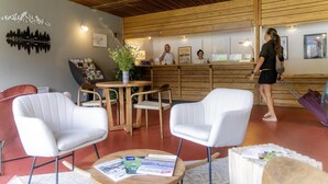 Una zona de recepción con paneles de madera, un mostrador de recepción y varias sillas blancas.
