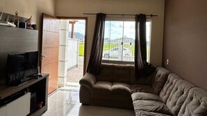 Un soggiorno con un divano componibile, una TV a schermo piatto su un mobile e una porta vetrata scorrevole che dà su una zona esterna.