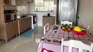 Una cucina compatta con mobili in legno, un frigorifero e un tavolo da pranzo con tovaglia a quadretti.