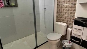 Bagno con doccia vetrata, toilette e lavandino.