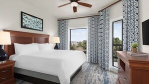 A hotel room with a large bed, a ceiling fan, patterned curtains, and a view of the outdoors. - Enjoyable 2-bedroom hotel in Hilton Head Island with WiFi (Hilton Head Island)
