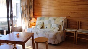 A cozy room with a wooden wall, a sofa with floral upholstery, a small table, and two chairs. - 10m from ski slopes, 1st floor, view ski slopes, balcony, tv, ski locker, 30m², Risoul (Risoul)