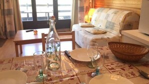 A dining area with a table set for four, a bottle, and a bowl. - 10m from ski slopes, 1st floor, view ski slopes, balcony, tv, ski locker, 30m², Risoul (Risoul)
