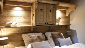 Ein Interieur einer Holzhütte mit einem Bett, Kissen und einem Regal mit Dekorationen.