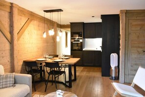 A cozy, well-lit dining area with a wooden table set for four, flanked by dark wooden cabinets and a modern kitchen in the background.