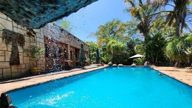 A clear blue pool with a stone wall on one side and lush greenery in the background. - Mukurumanzi Lodge (Polokwane)