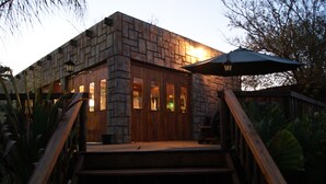 A stone building with a wooden staircase and an umbrella. - Mukurumanzi Lodge (Polokwane)