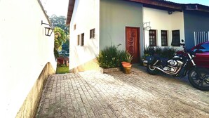 A paved courtyard with a motorcycle parked by a building with a tiled roof. - Casa de Alto Padrão no Jd Marajoara (São Paulo)